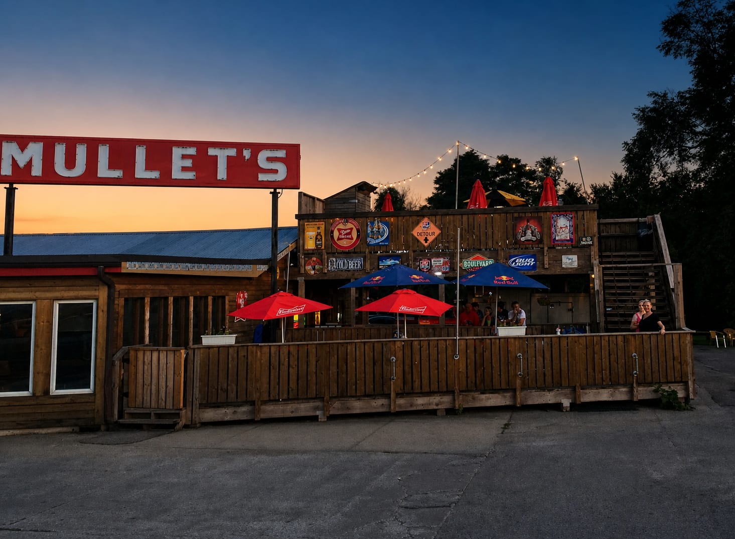 Mullet's sign and patio at dusk with string lights and umbrellas